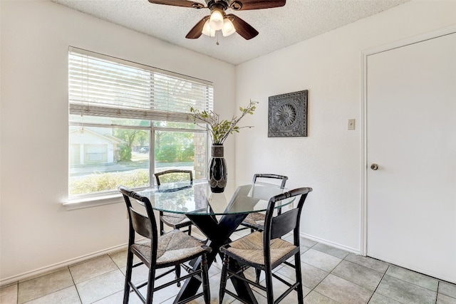 dining room featuring ceiling fan, plenty of natural light, light tile patterned floors, and a textured ceiling