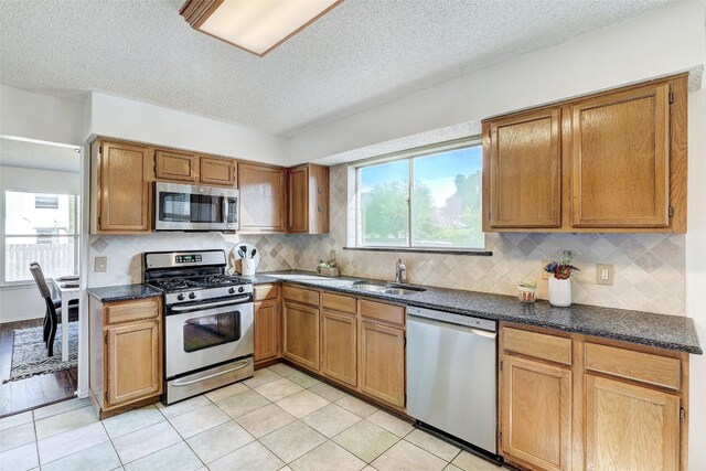 kitchen featuring a textured ceiling, stainless steel appliances, light tile patterned floors, and tasteful backsplash