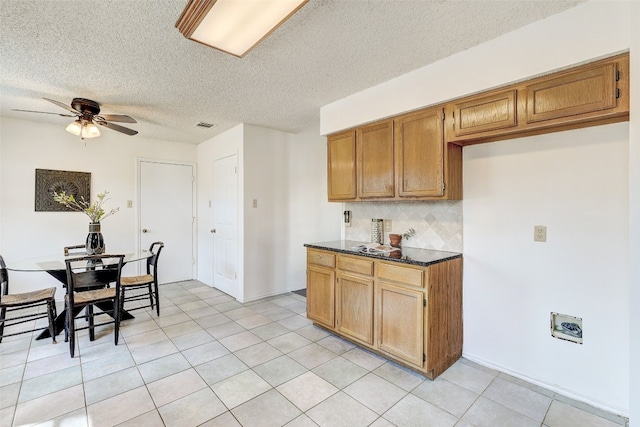 kitchen with a textured ceiling, light tile patterned floors, backsplash, and ceiling fan