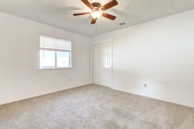 spare room with a textured ceiling, carpet, and ceiling fan