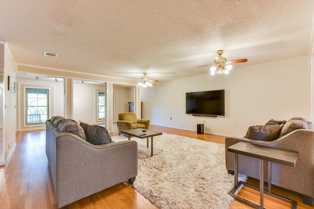 living room featuring light wood-type flooring, a textured ceiling, and ceiling fan