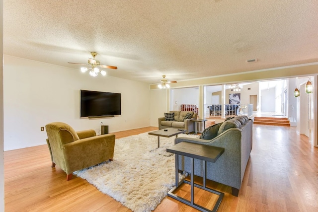 living room with ceiling fan, a textured ceiling, and hardwood / wood-style floors