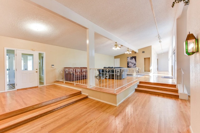 entryway with wood-type flooring, vaulted ceiling with beams, a textured ceiling, and ceiling fan