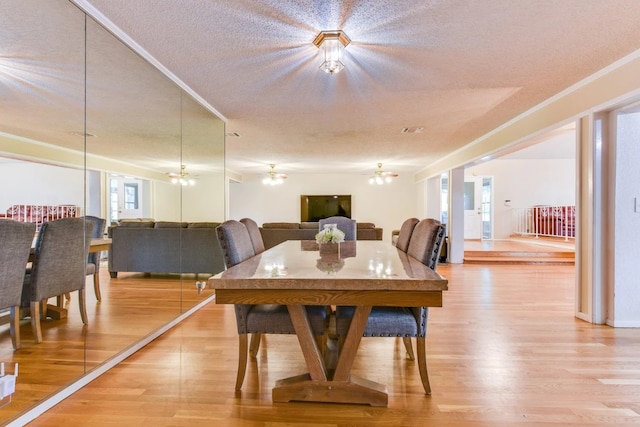 dining room featuring a textured ceiling, wood-type flooring, and ornamental molding