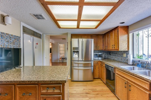 kitchen featuring stainless steel fridge, light hardwood / wood-style floors, backsplash, black dishwasher, and a textured ceiling