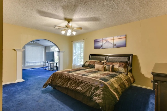 carpeted bedroom with ceiling fan, a textured ceiling, and decorative columns