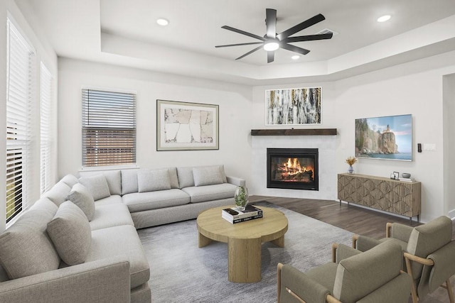 living room with hardwood / wood-style flooring, ceiling fan, and a tray ceiling