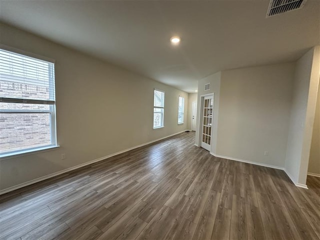 unfurnished room featuring visible vents, dark wood-type flooring, and baseboards