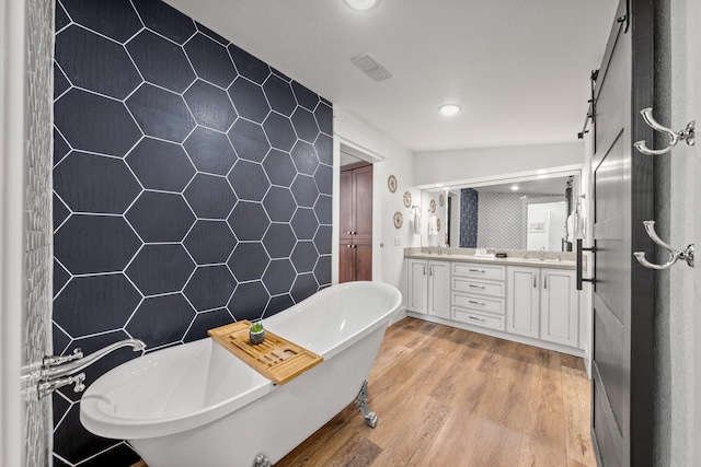 bathroom with a bathtub, vanity, tile walls, and hardwood / wood-style floors