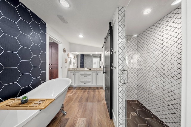 bathroom featuring hardwood / wood-style floors, independent shower and bath, lofted ceiling, tile walls, and vanity