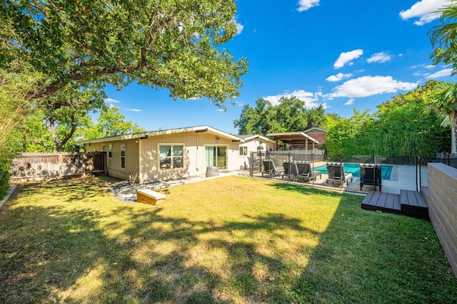 rear view of house with a pool side deck and a lawn