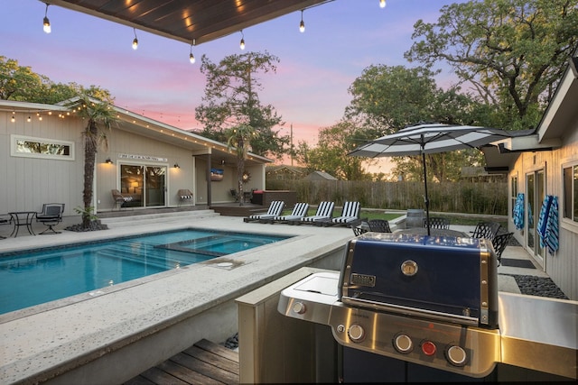 pool at dusk featuring a grill, a patio, and an in ground hot tub