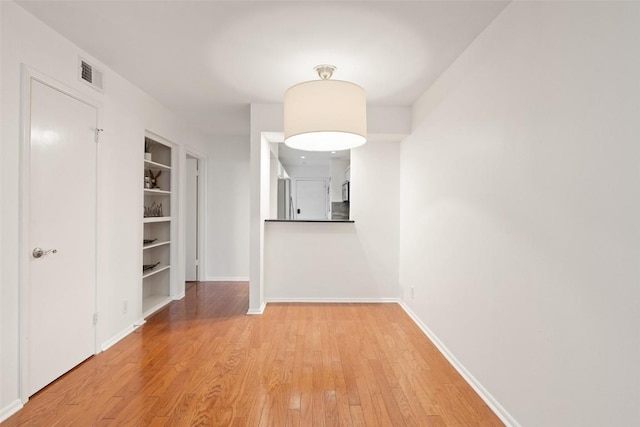 hall featuring built in shelves and light wood-type flooring