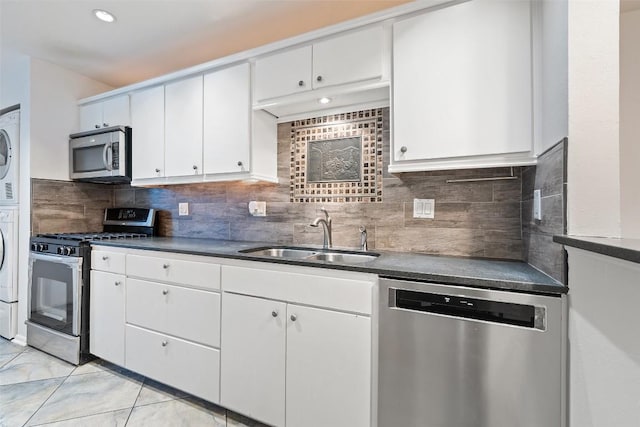 kitchen with tasteful backsplash, stainless steel appliances, sink, stacked washer and clothes dryer, and white cabinets