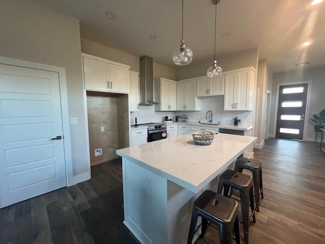 kitchen featuring stainless steel range with electric stovetop, white cabinets, sink, wall chimney exhaust hood, and a kitchen island