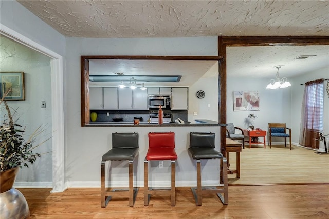 1807 Briar Hill Dr Unit A & B, Austin, TX 78741 - kitchen with stainless steel microwave, dark countertops, light wood finished floors, a chandelier, and a textured ceiling
