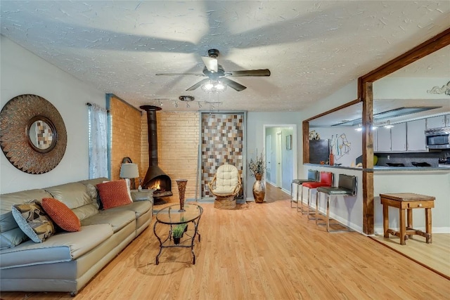 1807 Briar Hill Dr Unit A & B, Austin, TX 78741 - living room featuring wood finished floors, a wood stove, ceiling fan, a textured ceiling, and baseboards