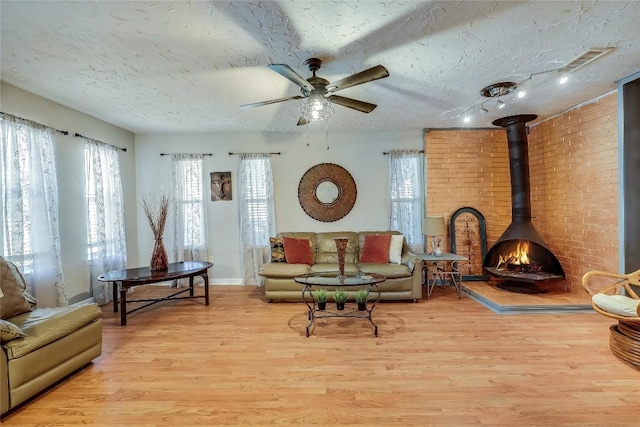 1807 Briar Hill Dr Unit A & B, Austin, TX 78741 - living room featuring wood finished floors, a textured ceiling, a ceiling fan, baseboards, and a wood stove