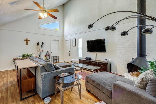 1807 Briar Hill Dr Unit A & B, Austin, TX 78741 - living area with a wood stove, light wood-type flooring, a ceiling fan, high vaulted ceiling, and a textured ceiling