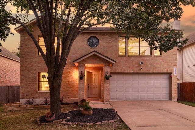 view of front facade with brick siding, fence, driveway, and an attached garage