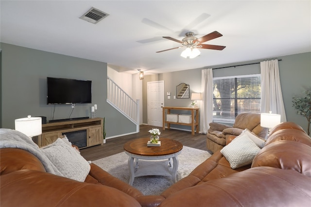 living room featuring dark wood-type flooring and ceiling fan