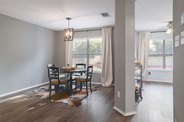 dining space featuring dark wood-type flooring and ceiling fan with notable chandelier