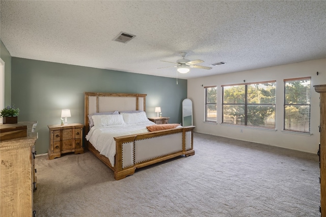 bedroom with a textured ceiling, light colored carpet, and ceiling fan