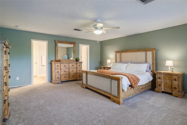 carpeted bedroom with a textured ceiling, ensuite bath, and ceiling fan