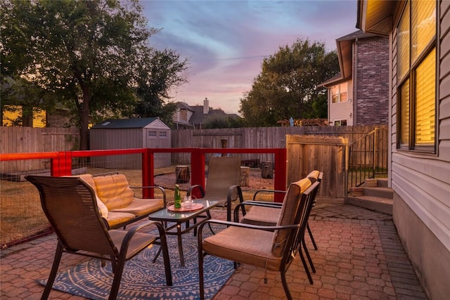 view of patio with a storage shed, a fenced backyard, and an outbuilding