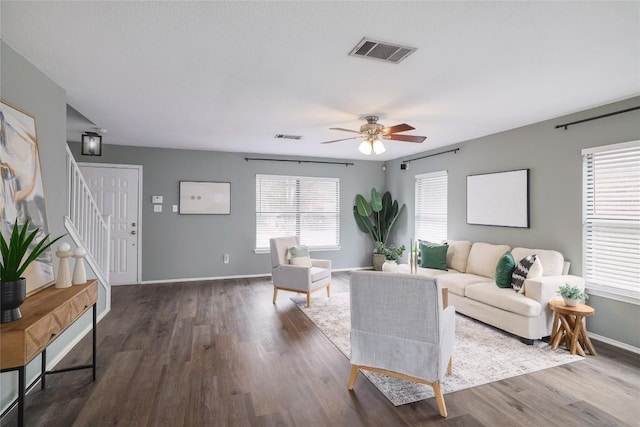 living area featuring baseboards, stairs, visible vents, and wood finished floors