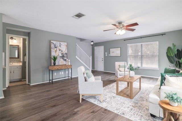 living room featuring visible vents, stairway, baseboards, and wood finished floors