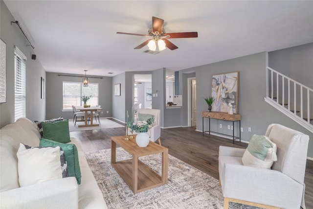 living room featuring stairs, ceiling fan, wood finished floors, and visible vents