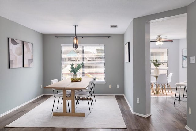 dining area with baseboards, visible vents, and dark wood-style flooring