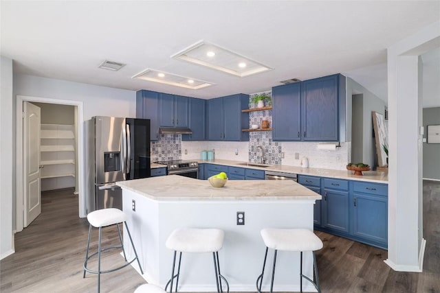 kitchen featuring blue cabinets, visible vents, stainless steel appliances, and a kitchen breakfast bar