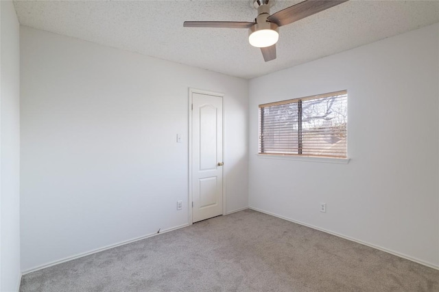 carpeted empty room featuring a textured ceiling, ceiling fan, and baseboards