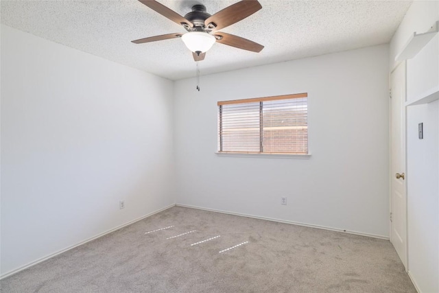 unfurnished room with baseboards, a ceiling fan, a textured ceiling, and light colored carpet