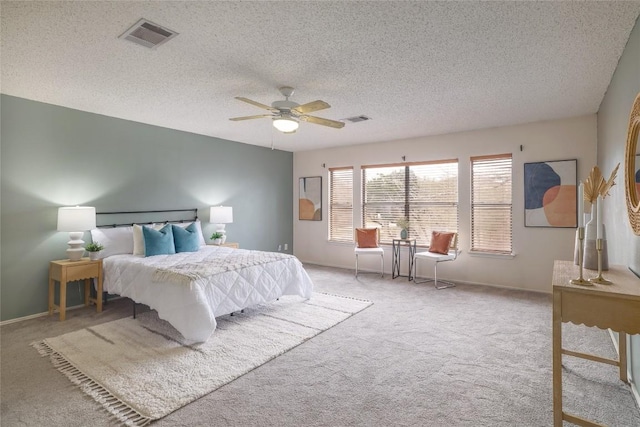 carpeted bedroom featuring a textured ceiling, ceiling fan, and visible vents