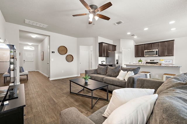 living room featuring ceiling fan, dark hardwood / wood-style floors, and a textured ceiling