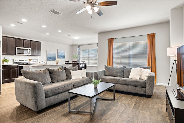 living room featuring ceiling fan, a textured ceiling, and hardwood / wood-style flooring