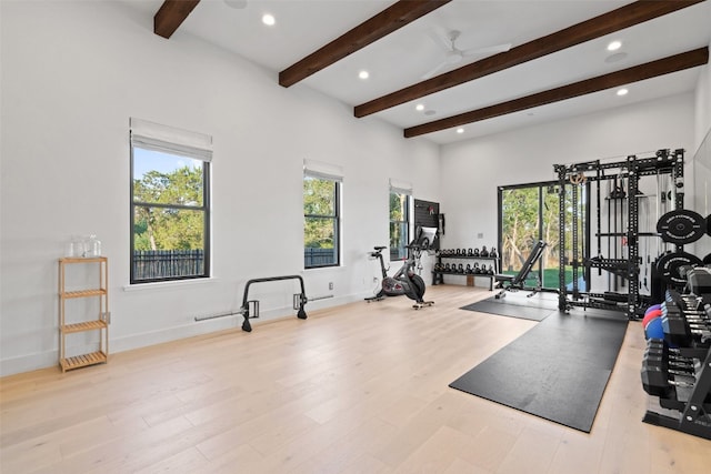 workout area with light hardwood / wood-style floors, a towering ceiling, and ceiling fan