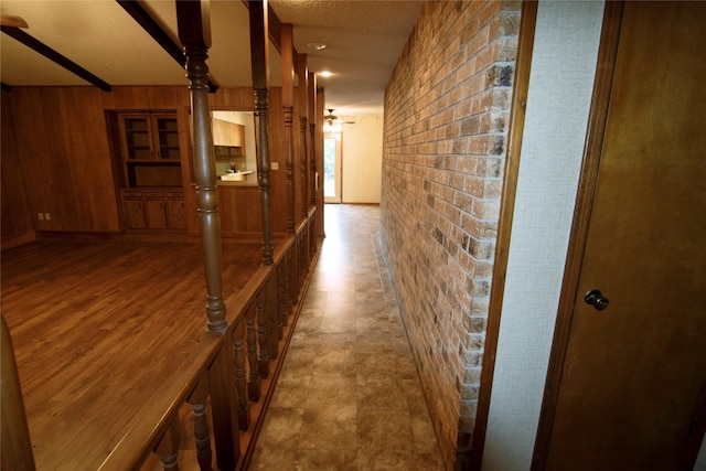 hall featuring a textured ceiling, wood-type flooring, and wood walls