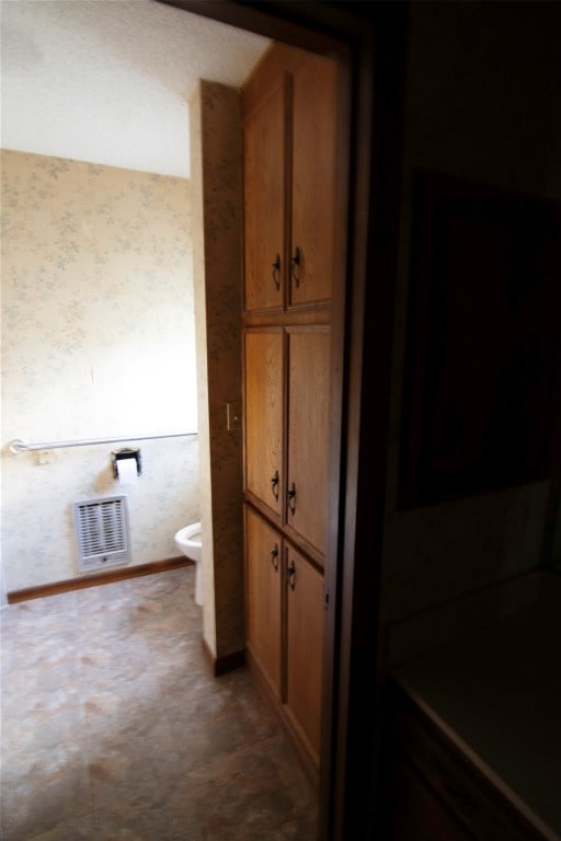 bathroom featuring heating unit and toilet