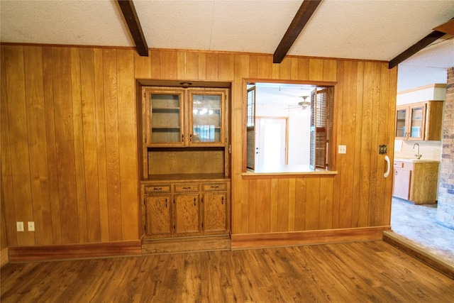 foyer with wood-type flooring, beamed ceiling, wooden walls, and a textured ceiling