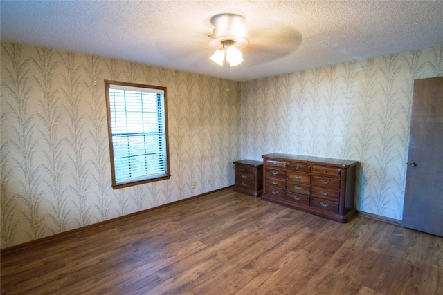 unfurnished room with ceiling fan, a textured ceiling, and dark hardwood / wood-style floors