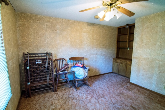 sitting room with ceiling fan, a textured ceiling, and carpet flooring