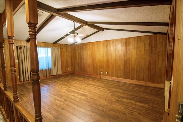 interior space with wood-type flooring, wood walls, ceiling fan, and lofted ceiling with beams