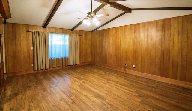 spare room featuring lofted ceiling with beams, wood walls, ceiling fan, and hardwood / wood-style flooring