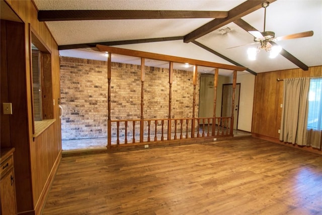 209 Simpson St, Schulenburg, TX 78956 - unfurnished room with beamed ceiling, a ceiling fan, wood finished floors, wooden walls, and brick wall