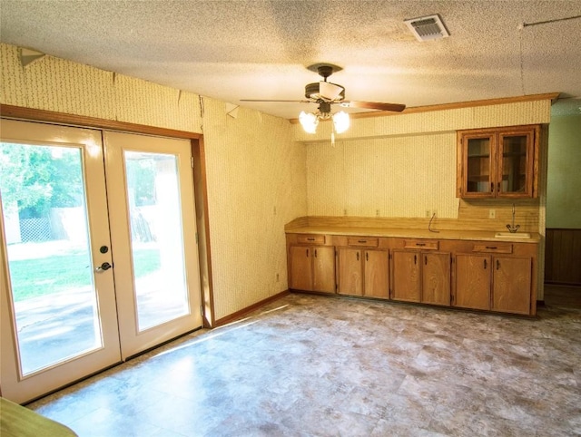 209 Simpson St, Schulenburg, TX 78956 - kitchen featuring french doors, brown cabinetry, light floors, ceiling fan, and a textured ceiling
