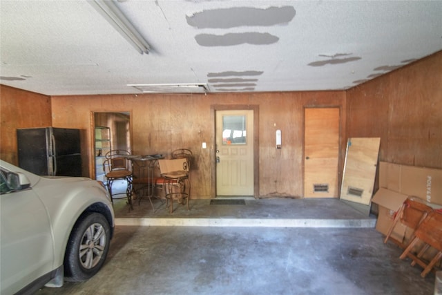 garage with wooden walls and black fridge